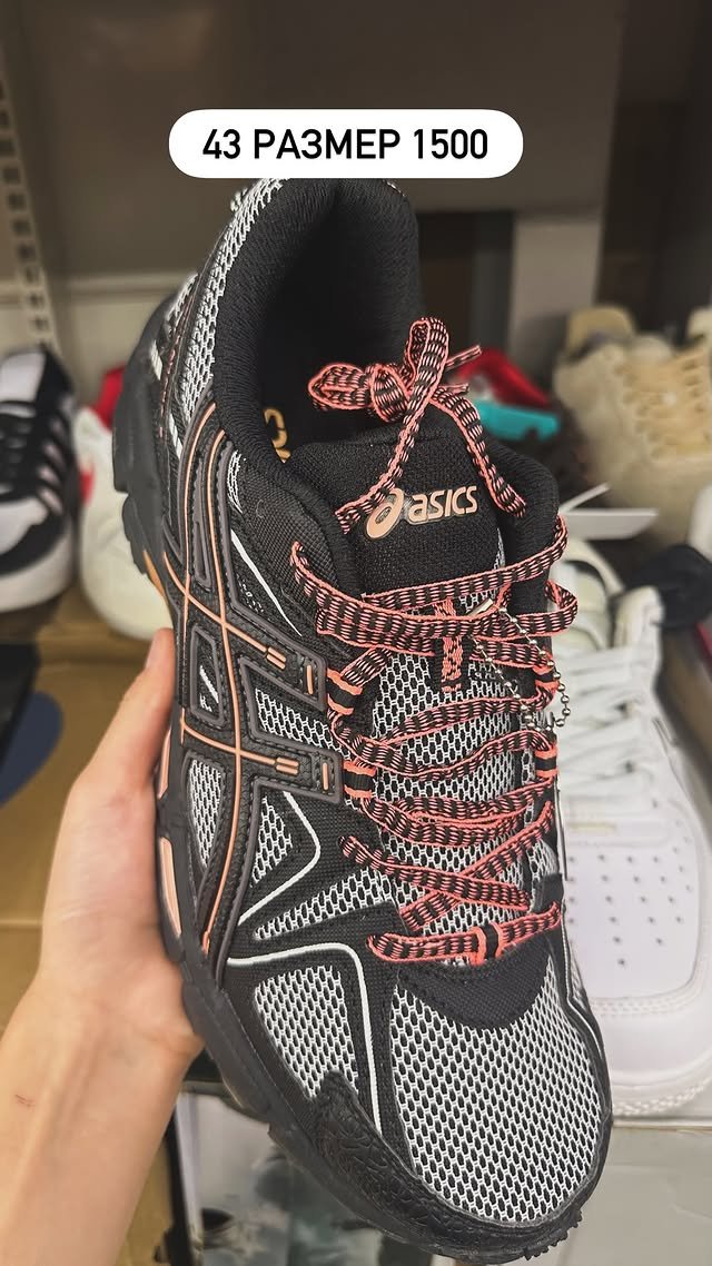 Кроссовки Asics черного цвета с оранжевыми элементами.